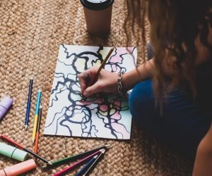 Person focused on drawing neurographic art, creating intricate lines and colorful shapes.
