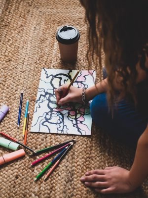 Person focused on drawing neurographic art, creating intricate lines and colorful shapes.